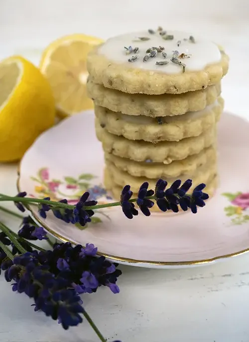 A stack of glazed lemon lavender shortbread cookies on a porcelain plate.