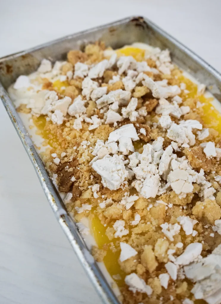 Layering ice cream, curd, shortbread bits, and meringue bits to make lemon meringue pie ice cream.