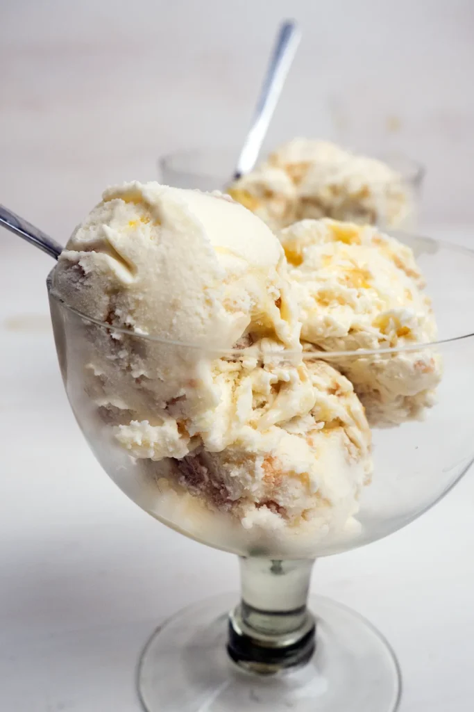 Scoops of lemon meringue pie ice cream in a glass.