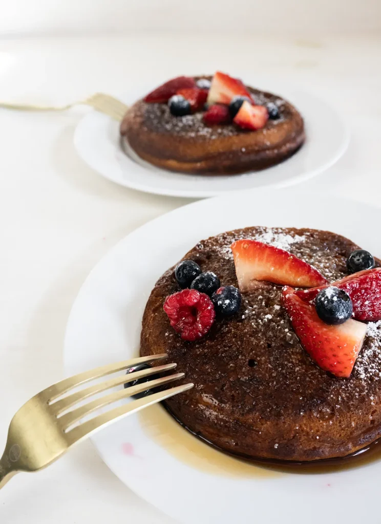Two plates with mini skillet pancakes topped with fresh berries.