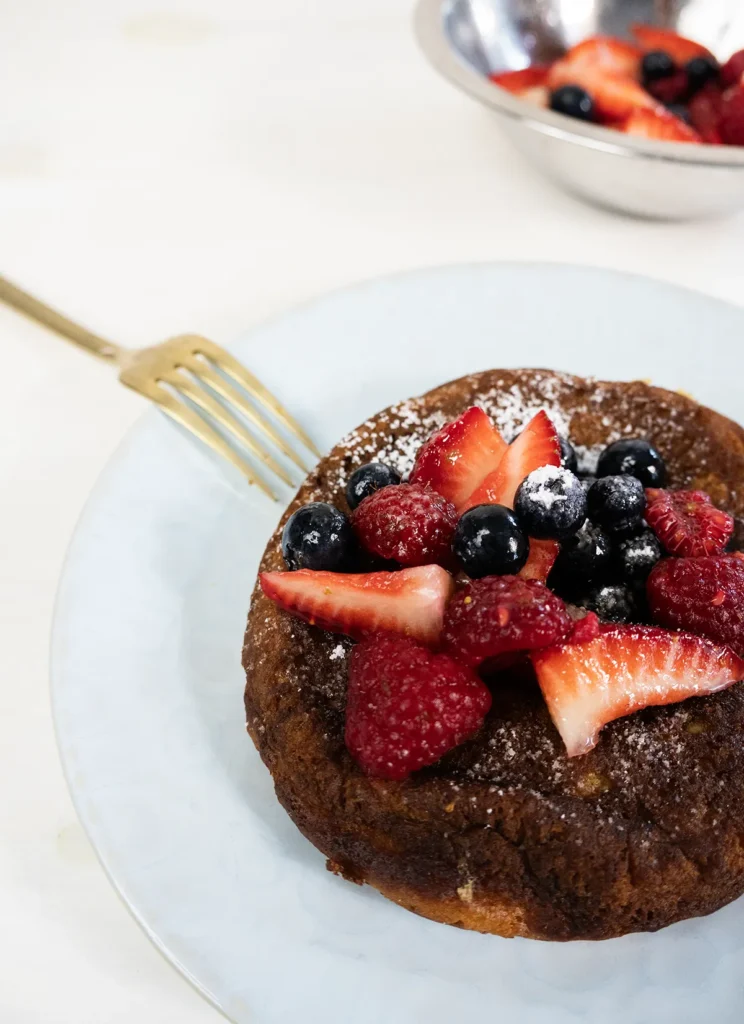 Mini skillet pancake on a plate with fresh berries.