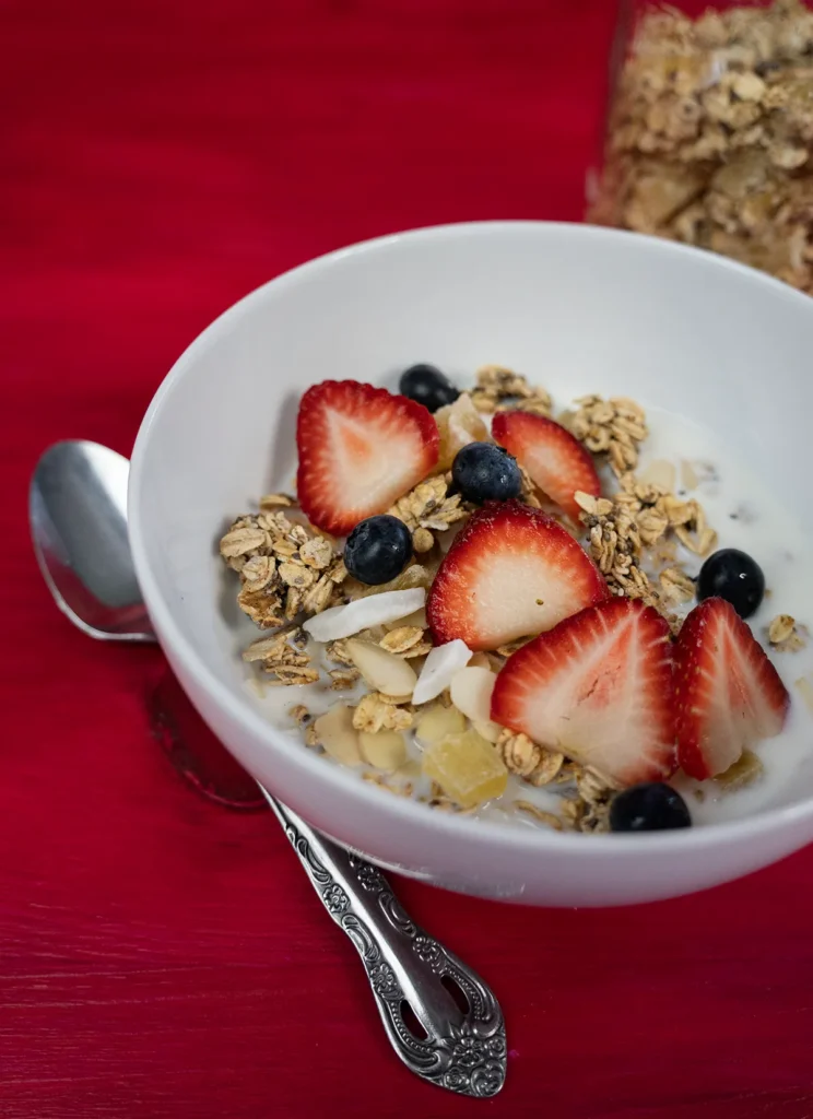 Bowl of sourdough granola topped with fresh strawberries and blueberries.