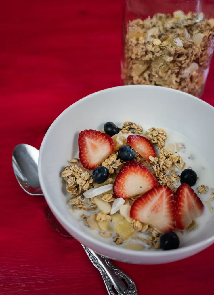 Bowl of sourdough granola topped with fresh strawberries and blueberries.