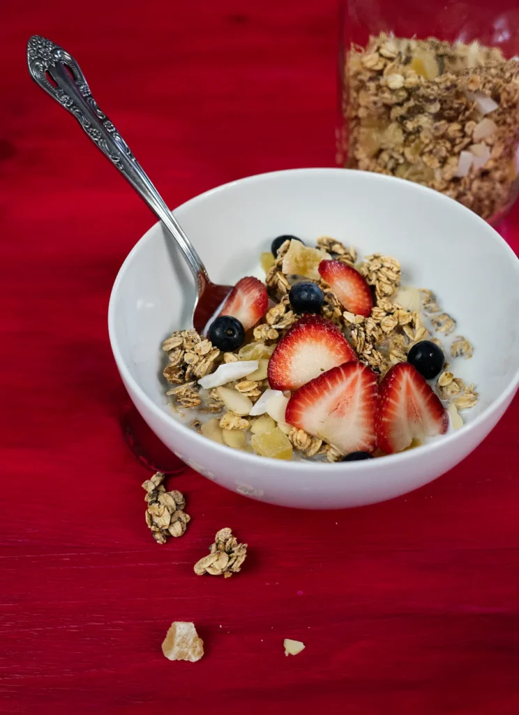 Bowl of sourdough granola topped with fresh strawberries and blueberries.