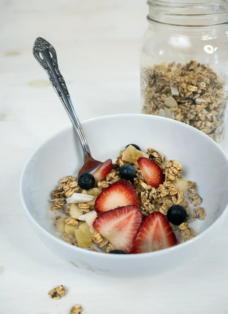 Bowl of sourdough granola topped with fresh strawberries and blueberries.