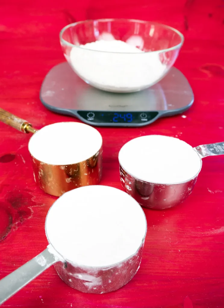 Weighing cups of flour on a digital scale.
