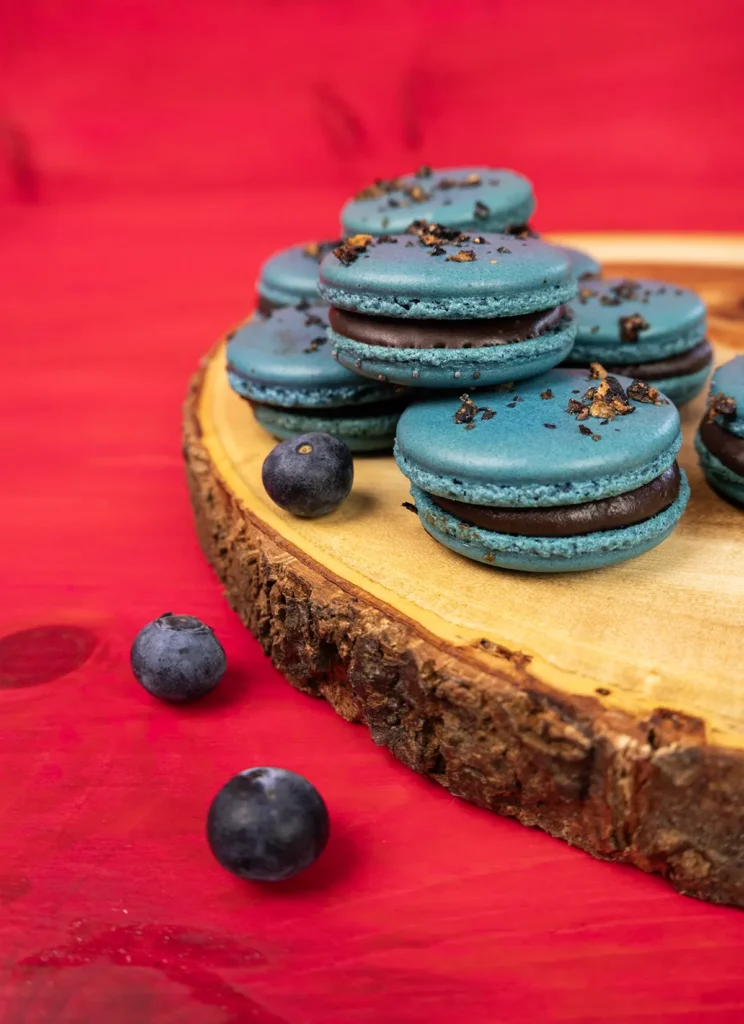 Blueberry macarons on a wooden plate.
