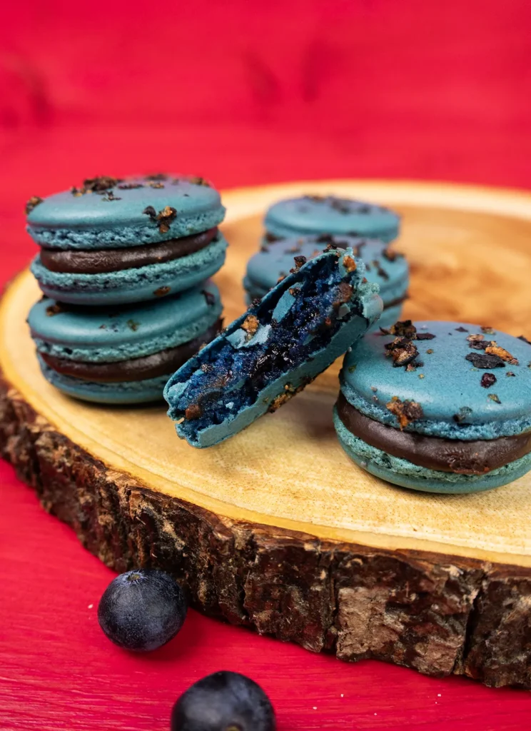 Blueberry macarons arranged on a wooden plate.