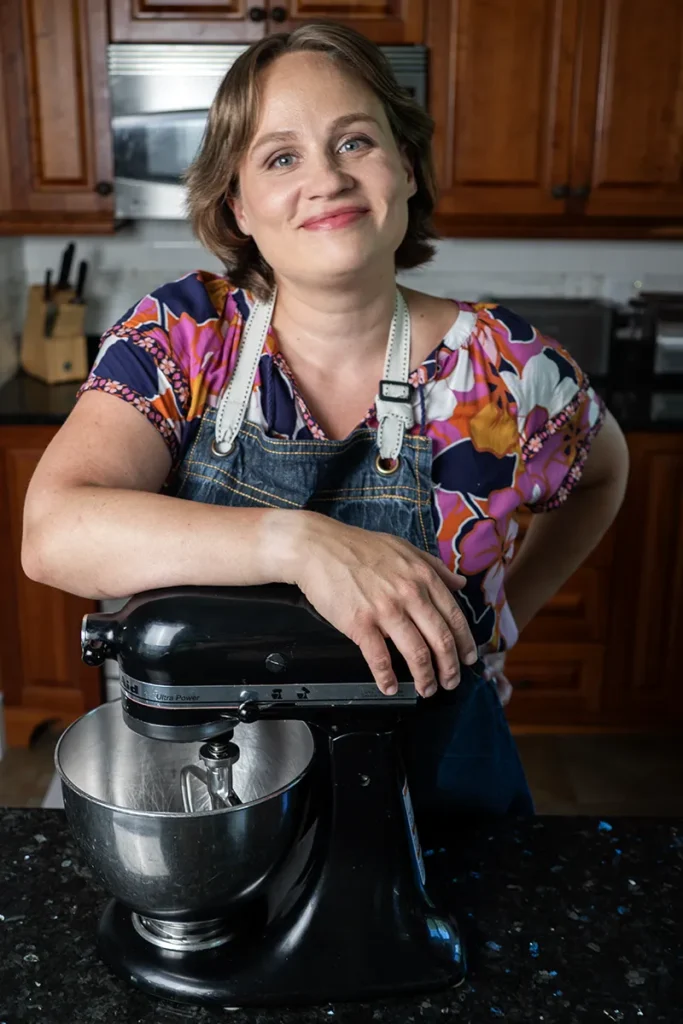 Joanna Rankin with an arm over a Kitchen-Aid stand mixer.