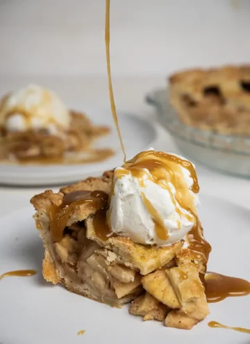 Slice of miso caramel apple pie with a scoop of ice cream, getting drizzled with miso caramel.