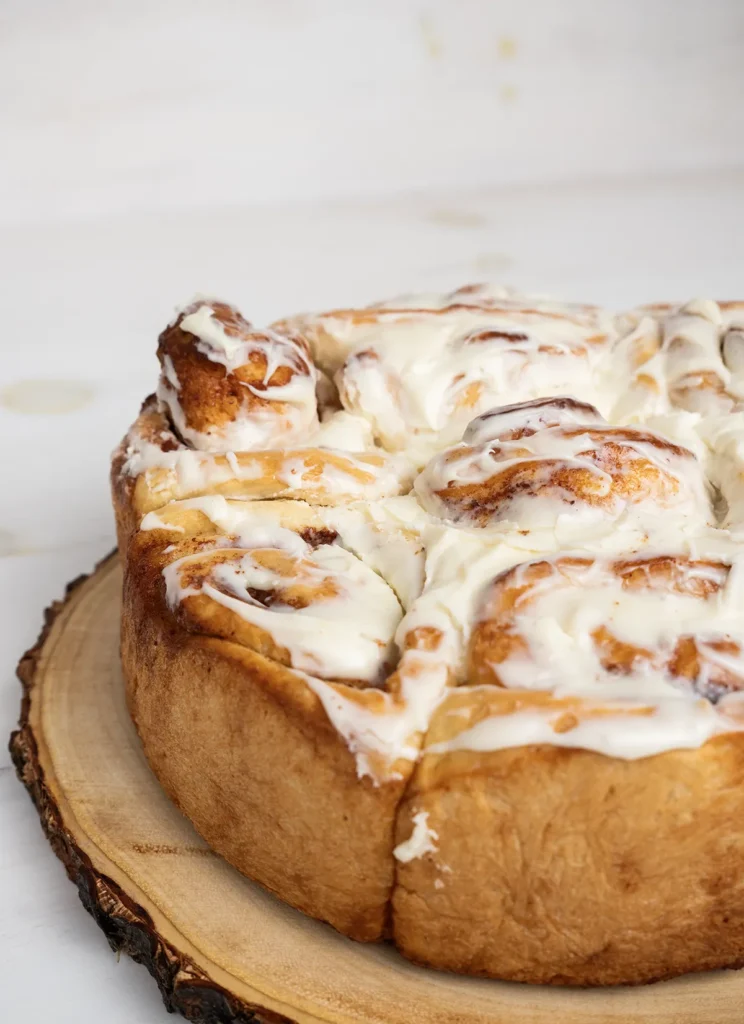 Close-up of cinnamon rolls with cream cheese frosting baked in a round cake pan.