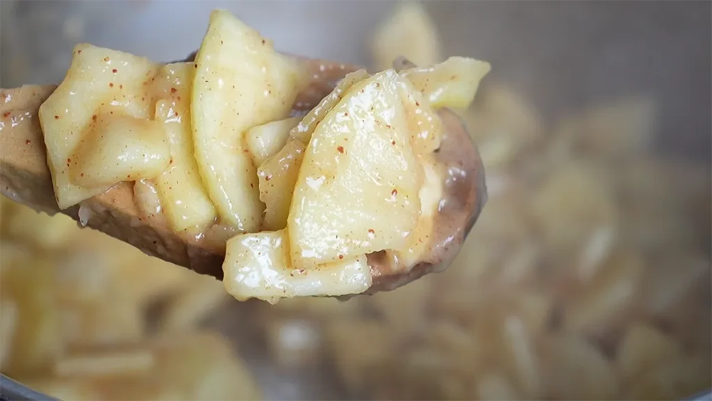 Cooked miso apple pie filling on a wooden spoon.
