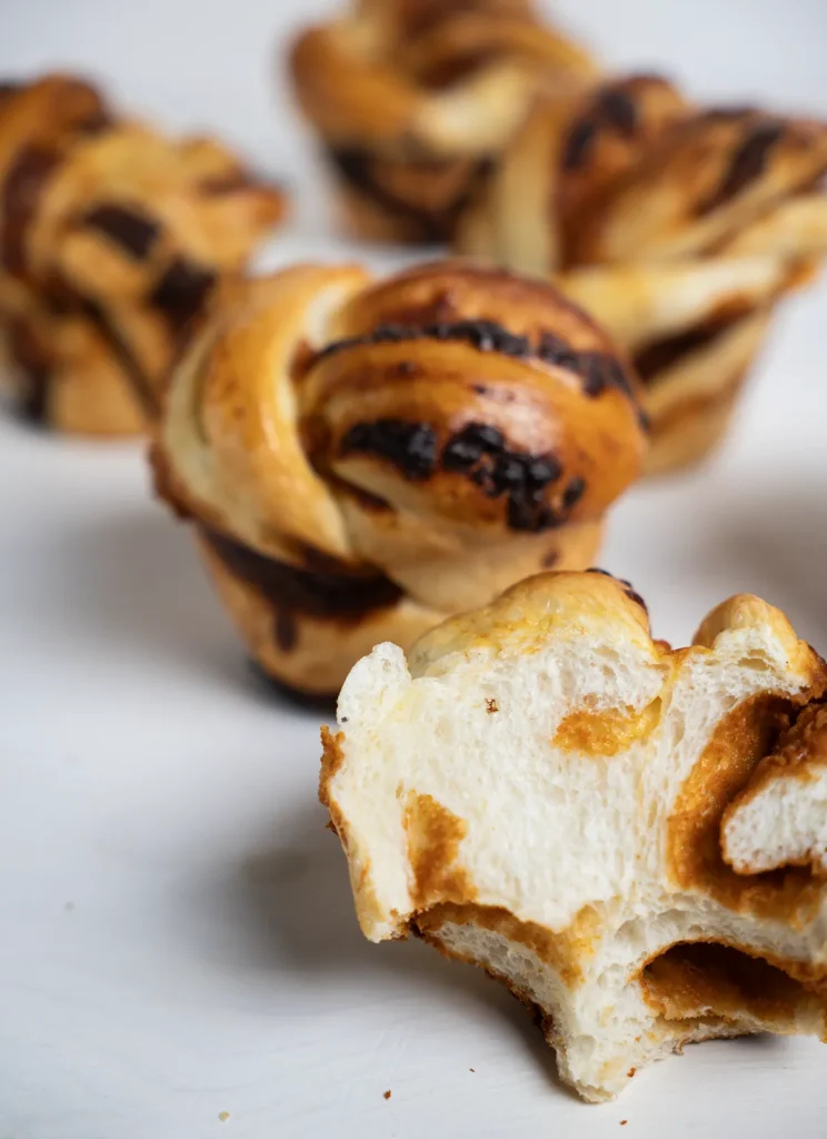 A group of gochujang cheddar mini babkas. One is cut open with a bite taken out of it.