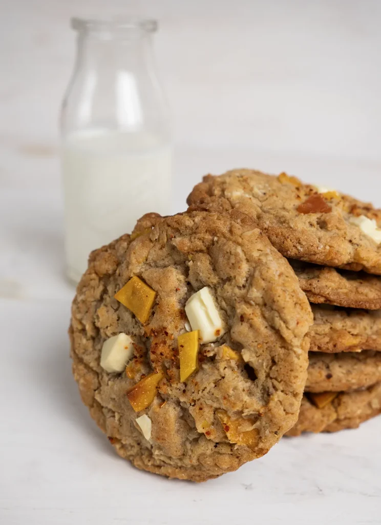 Stack of mango Tajin oatmeal cookies in front of a vintage milk bottle.