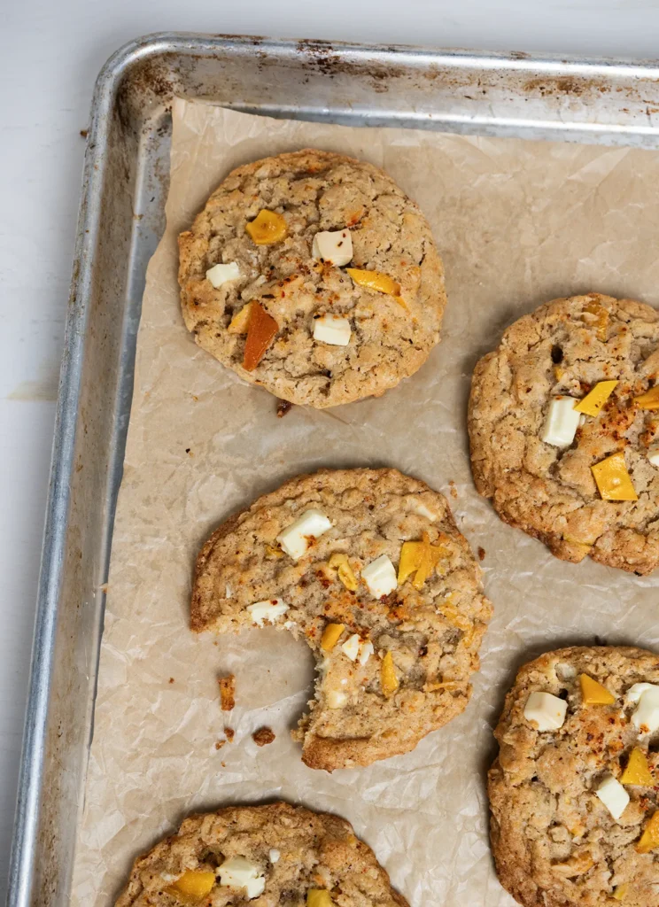 Baking sheet with Mango Tajin oatmeal cookies. One cookie has a bite taken out of it.