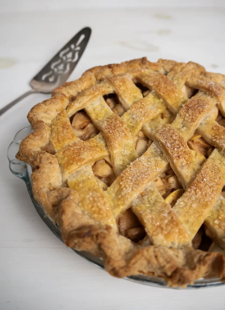 Miso caramel apple pie with a lattice crust, and a cake server in the background.
