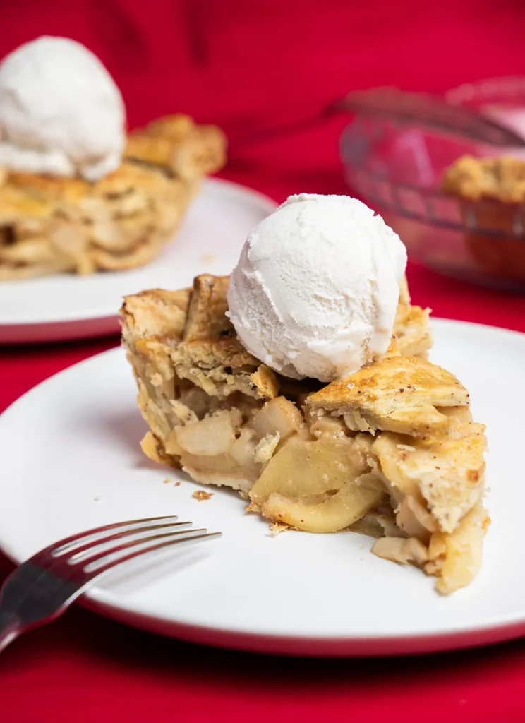 Slice of miso caramel apple pie with a scoop of ice cream.
