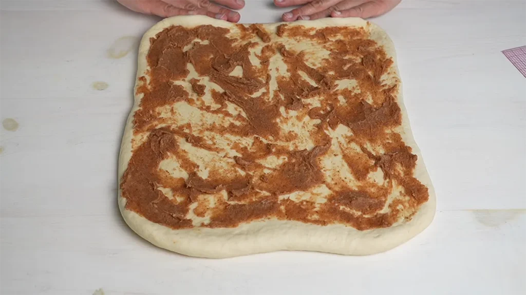 Spreading cinnamon sugar filling on a rectangle of dough.