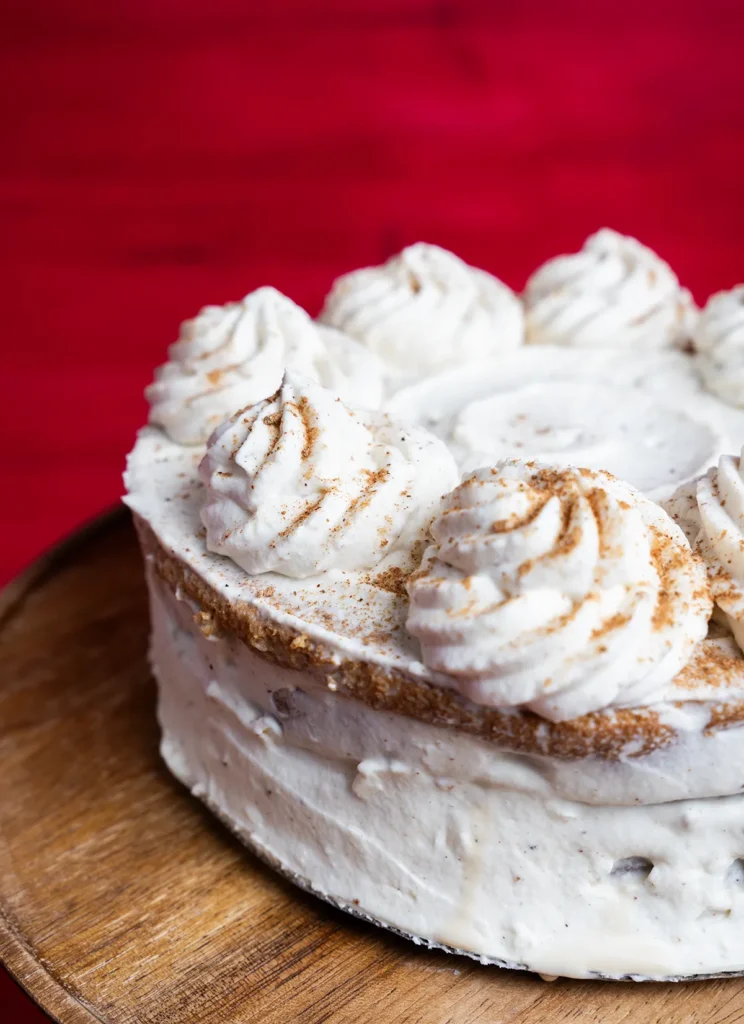 Pumpkin spice latte tres leches cake on a wooden cake stand.