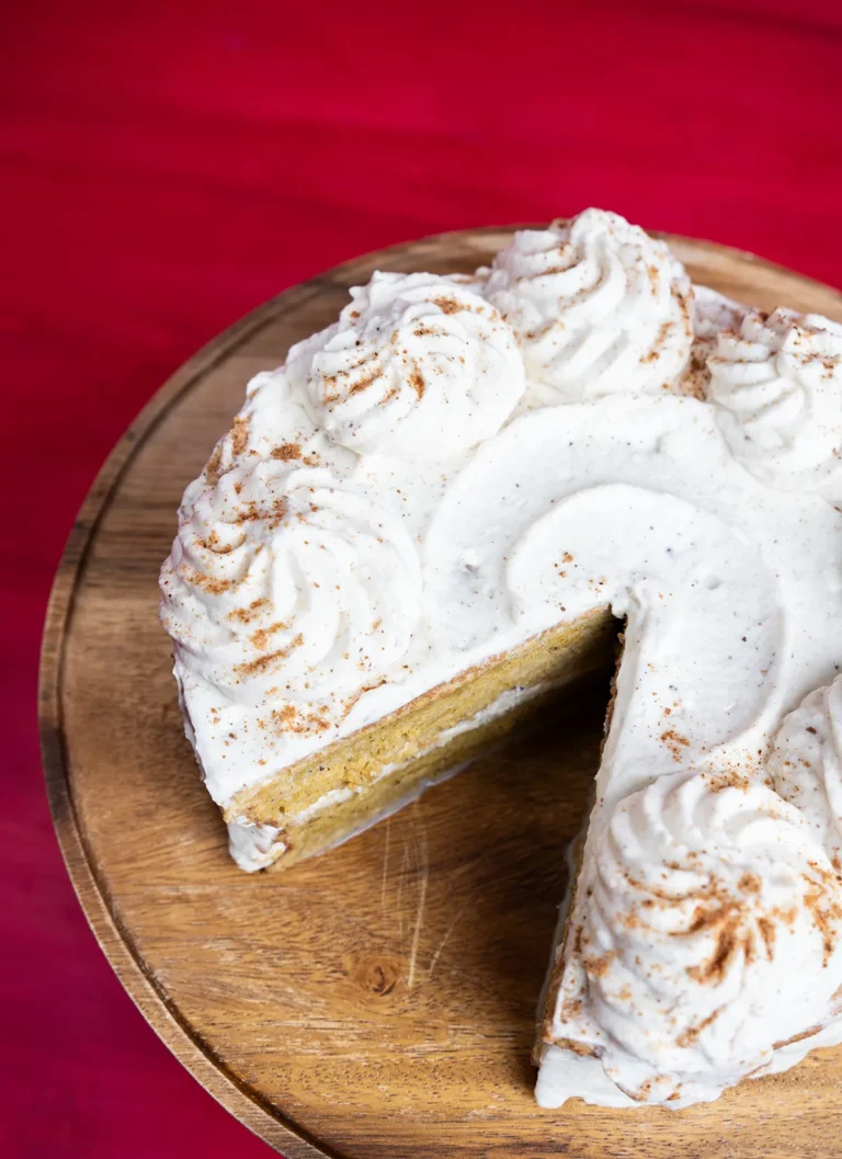 Top view of a pumpkin spice latte tres leches cake on a wooden cake stand, with a slice taken out.