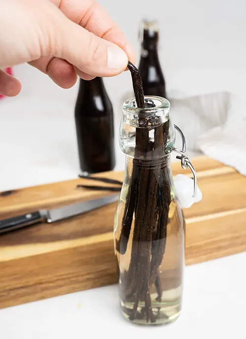 Putting a vanilla bean into a bottle to make extract.