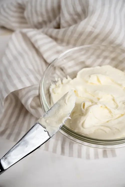 Container of mascarpone cheese with a butter knife.
