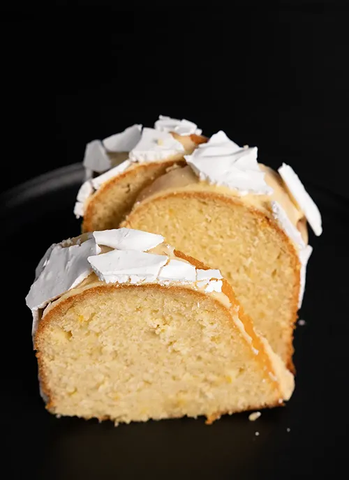 Slices of gourmet lemon bundt cake with preserved lemon and meringue shards.