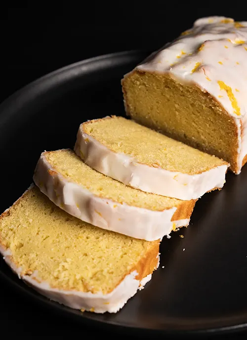 Sliced loaf of glazed lemon pound cake.