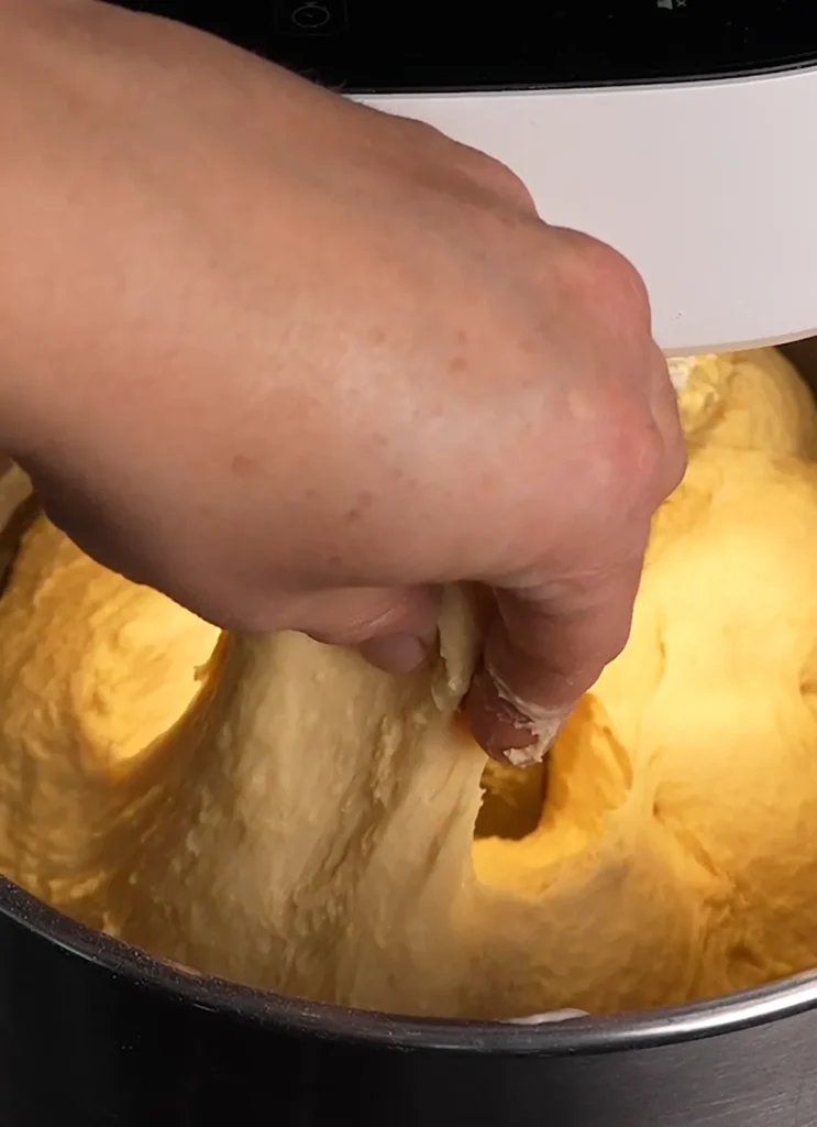 Pulling up on some enriched sourdough in a stand mixer to test its gluten strength.
