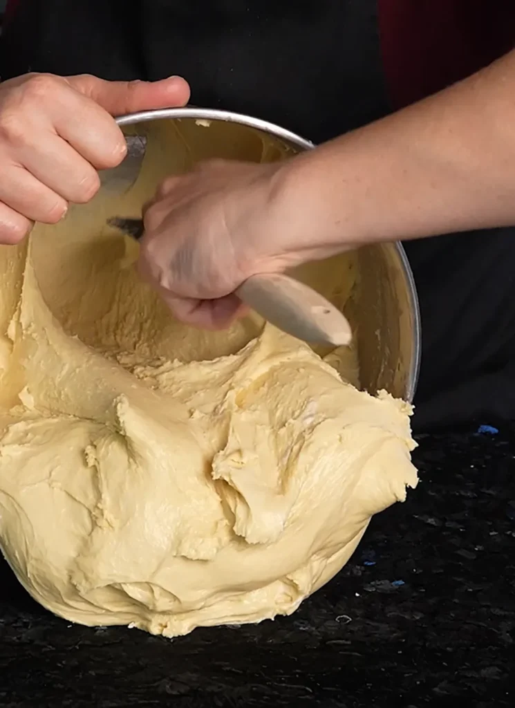 Removing enriched sourdough dough from a large stand mixer bowl.