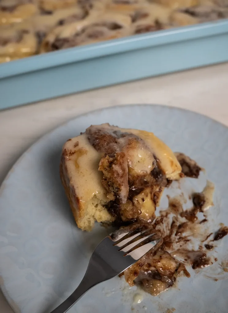 A cookie dough cinnamon roll on a plate with a fork.