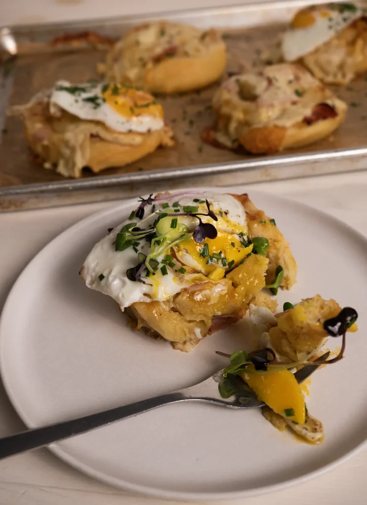 A forkful of croque madame roll on a plate, sprinkled with chopped chives.
