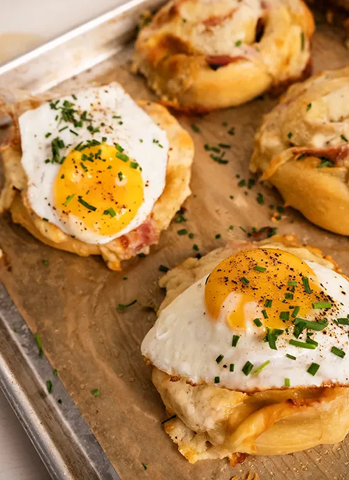 Croque Madame rolls on a baking sheet, sprinkled with chopped chives.