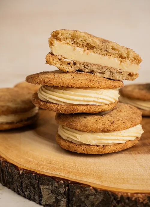 A stack of eggnog snickerdoodle sandwich cookies. One has a bite taken out of it.