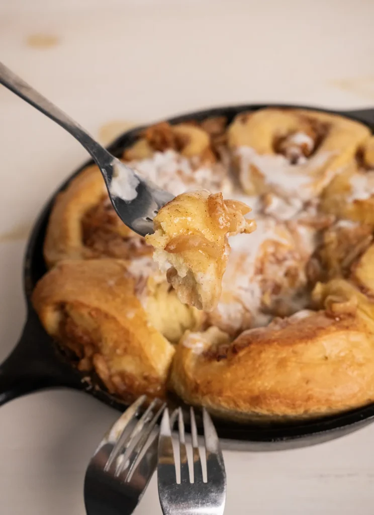 Three forks sharing a skillet of miso caramel apple pie cinnamon rolls.