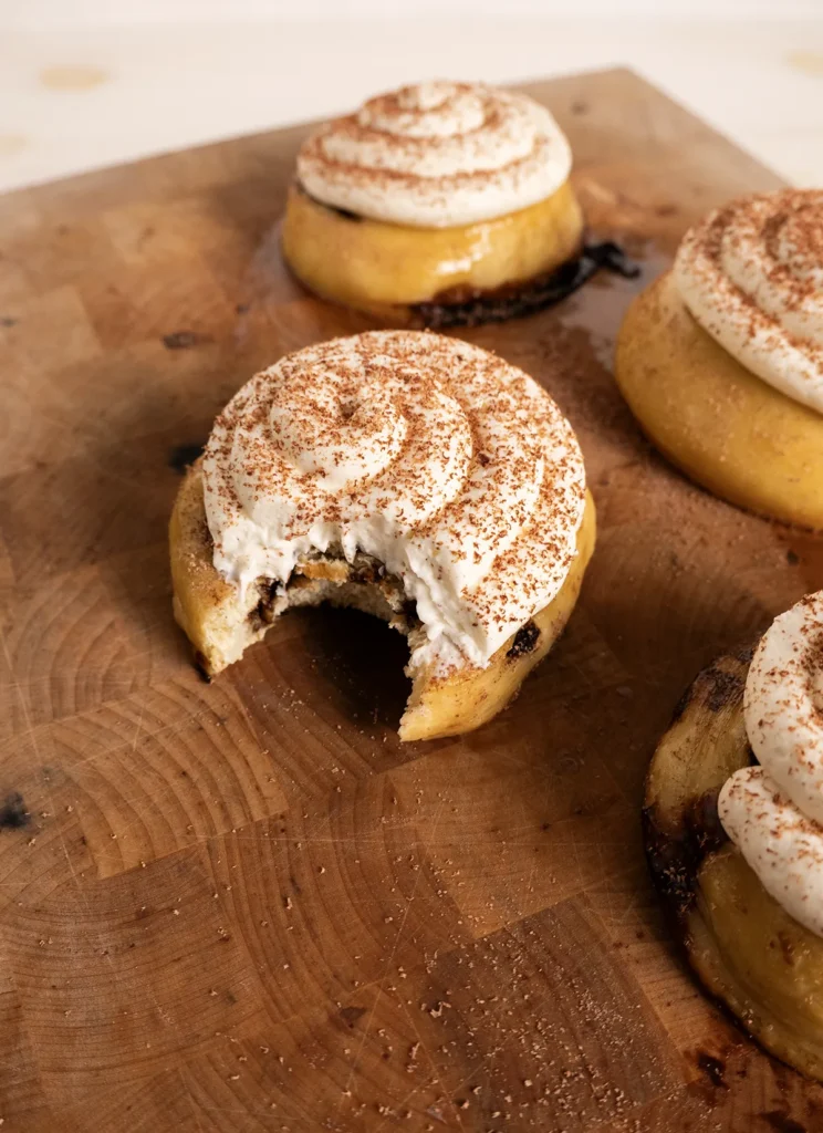 Sourdough tiramisu rolls with mascarpone frosting. One has a bite taken out of it.