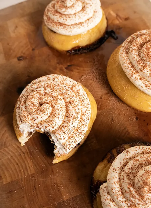 Sourdough tiramisu rolls with mascarpone frosting. One has a bite taken out of it.